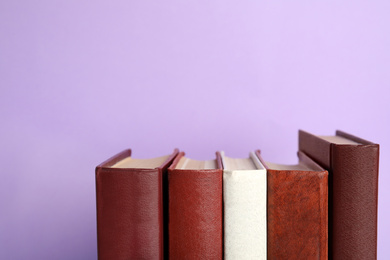 Photo of Collection of old books on violet background, space for text
