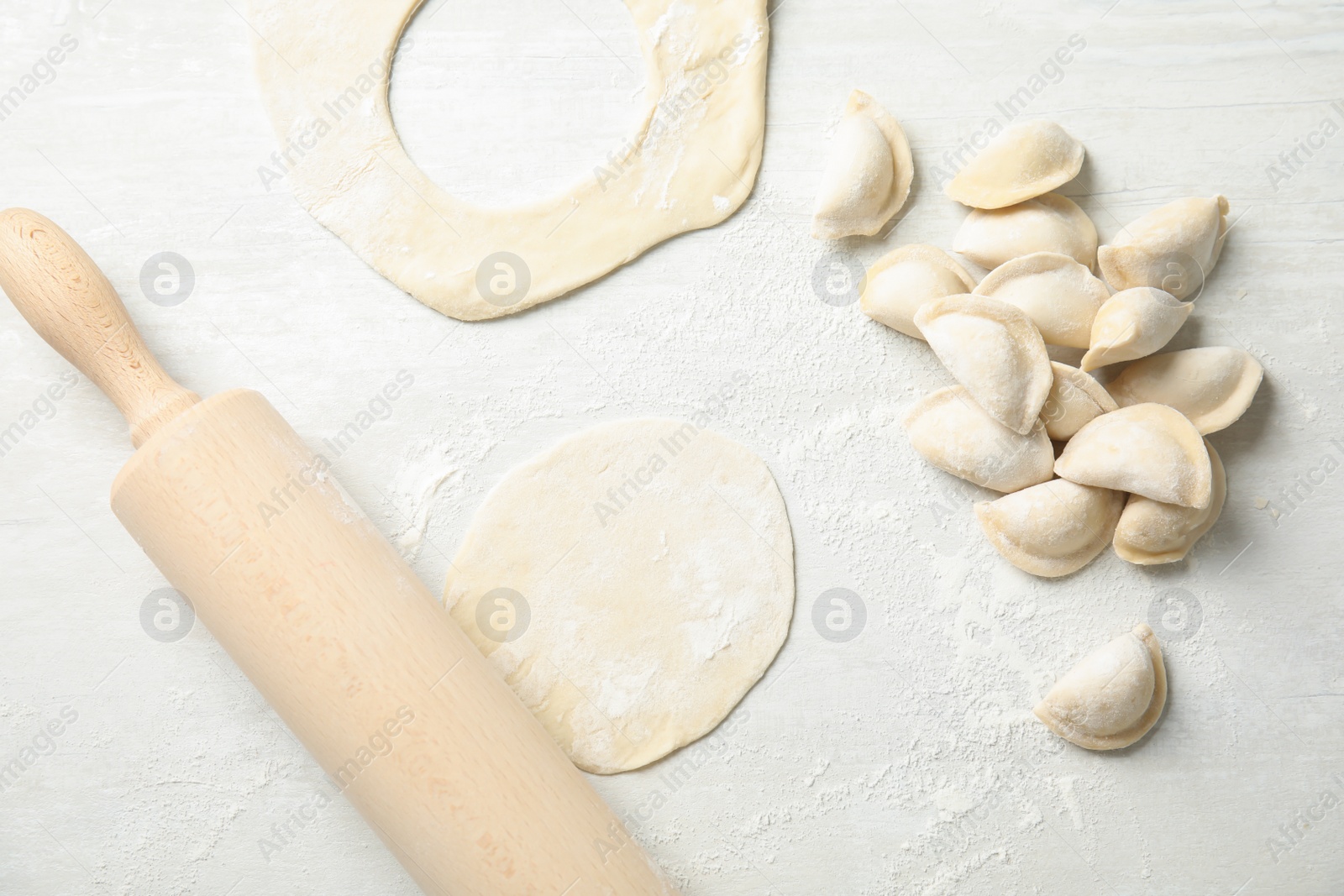 Photo of Flat lay composition with raw dumplings on light background. Process of cooking