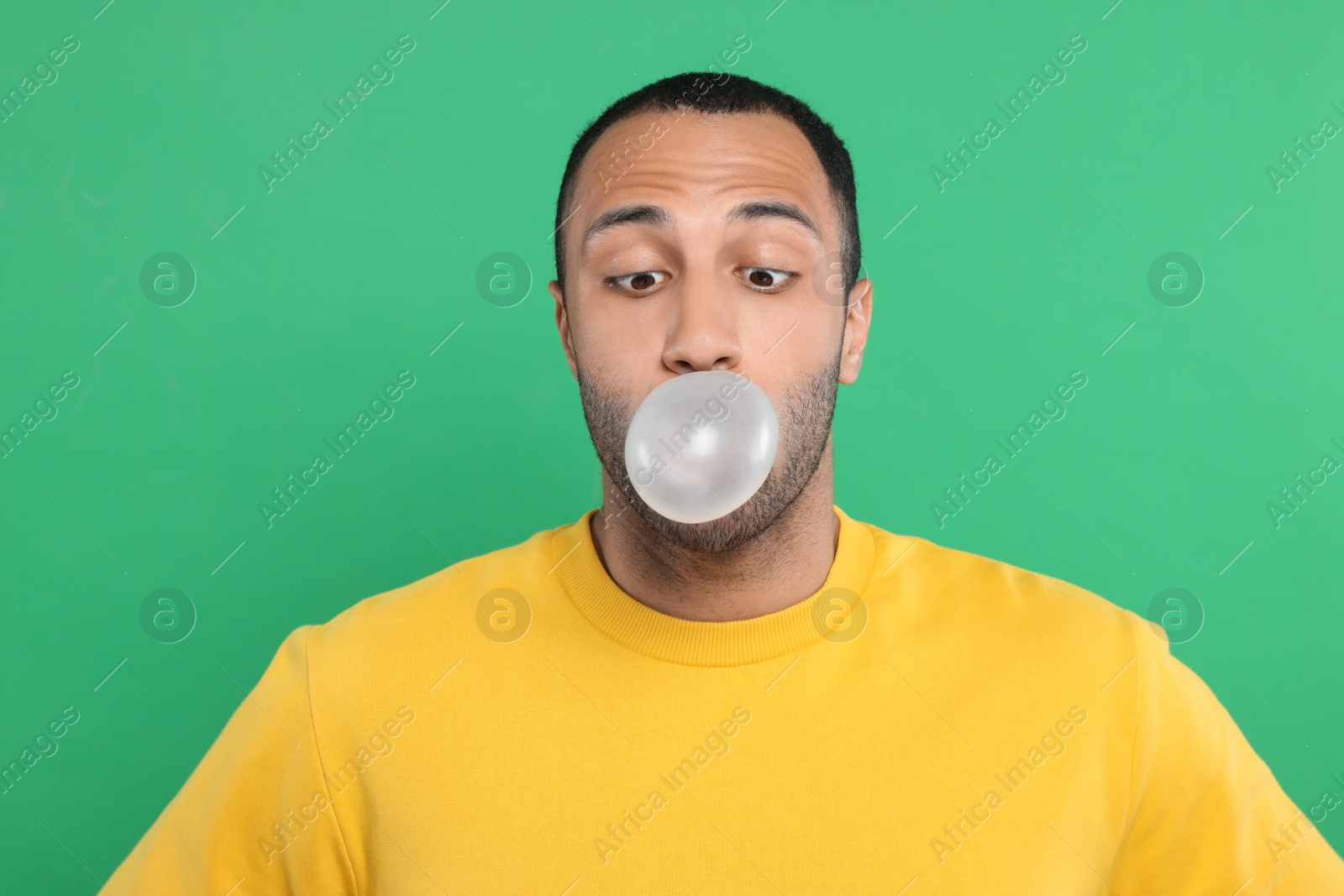 Photo of Portrait of young man blowing bubble gum on green background