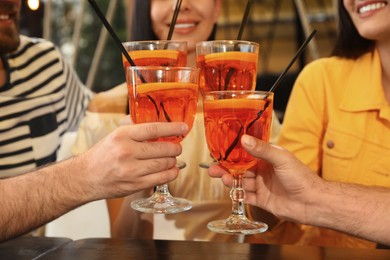 Friends with Aperol spritz cocktails resting together at restaurant, closeup