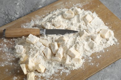 Making shortcrust pastry. Flour, butter, knife and wooden board on grey table