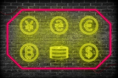 Money exchange neon sign. Pink frame with yellow symbols of different currencies on brick wall