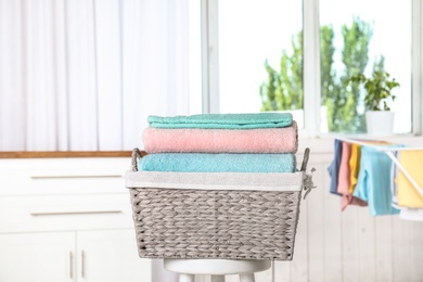Photo of Basket with clean laundry on stool at home