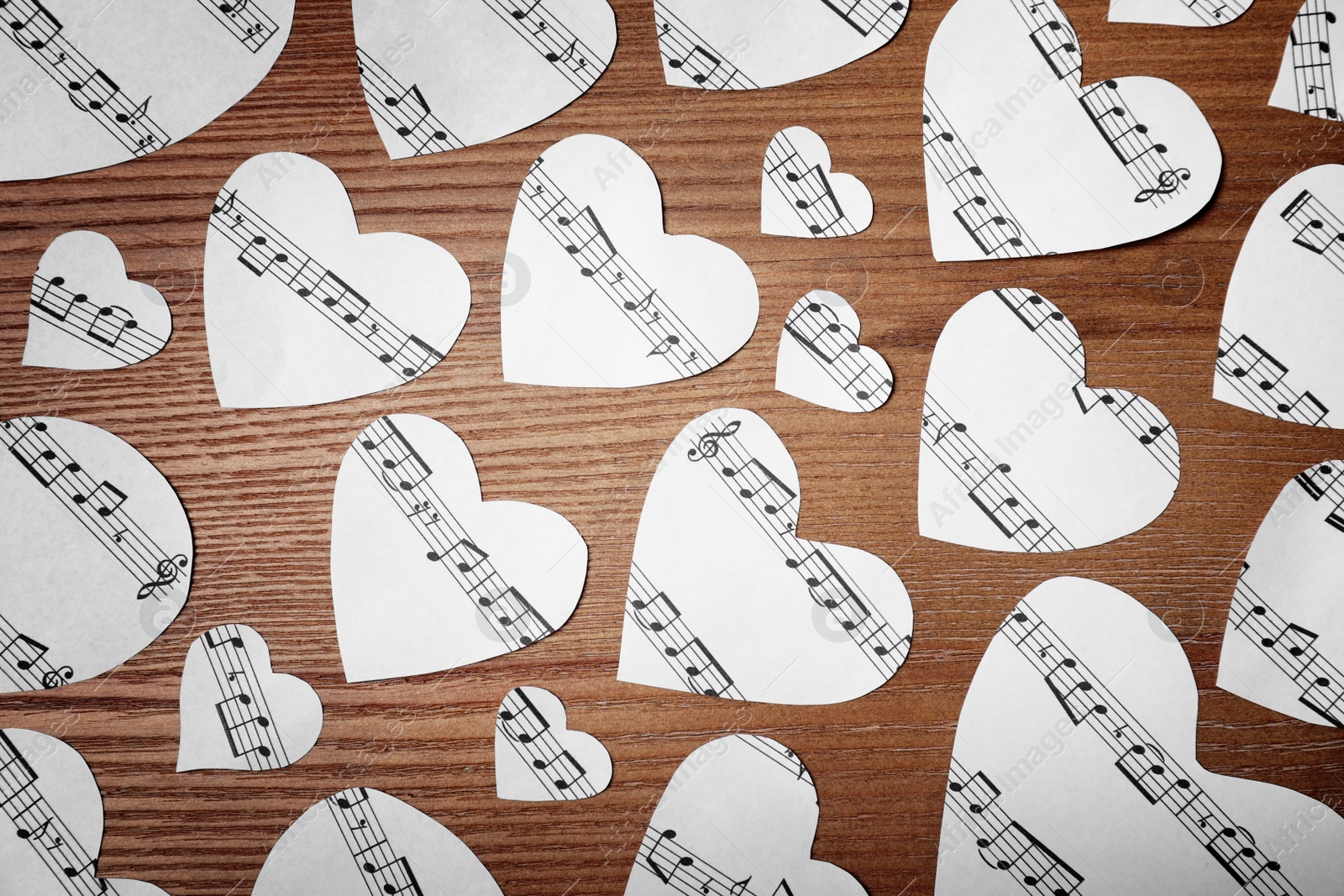 Photo of Paper hearts with music notes on wooden background, flat lay