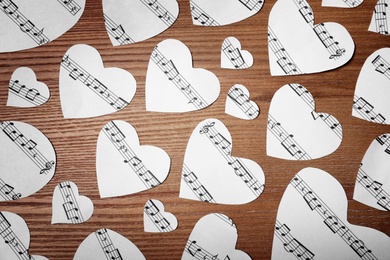 Paper hearts with music notes on wooden background, flat lay