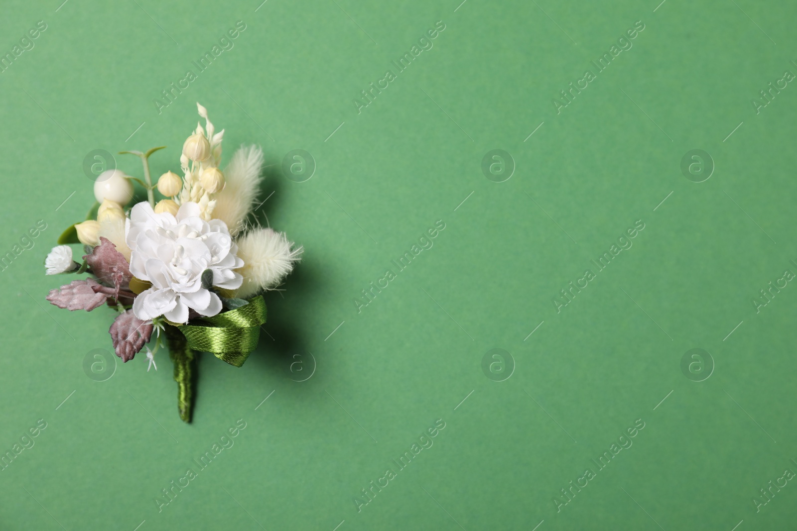 Photo of Stylish boutonniere on green background, top view. Space for text