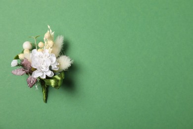 Stylish boutonniere on green background, top view. Space for text