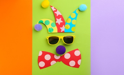 Photo of Flat lay composition clown's face made of sunglasses, hat and bow tie on color background