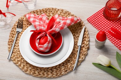 Photo of Festive table setting with bunny ears made of red egg and napkin. Easter celebration