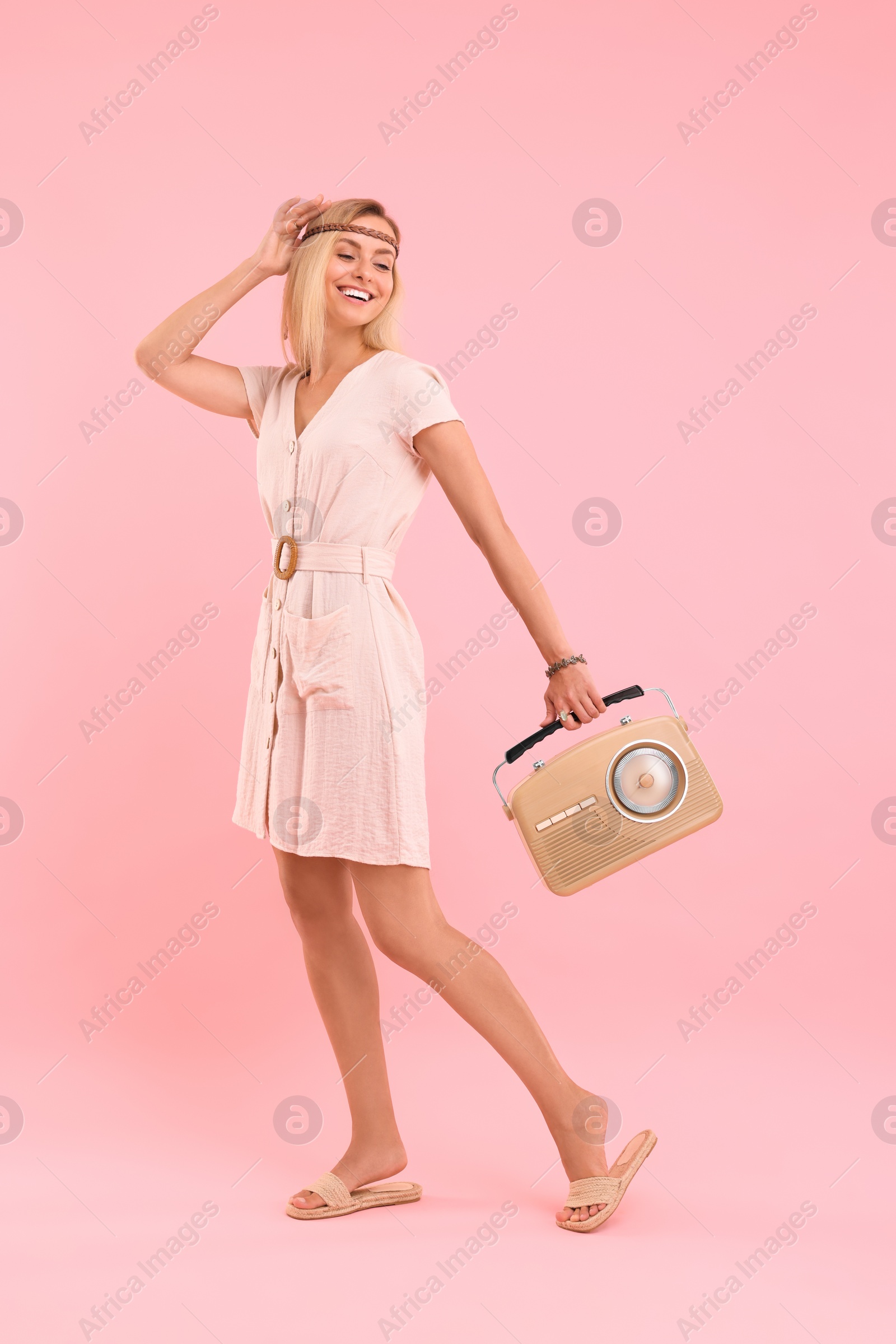 Photo of Happy hippie woman with retro radio receiver on pink background