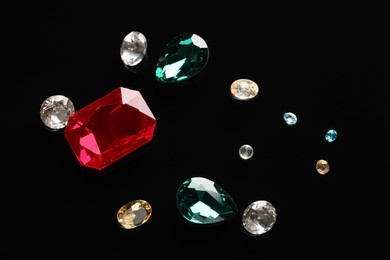 Photo of Different beautiful gemstones for jewelry on black background, flat lay