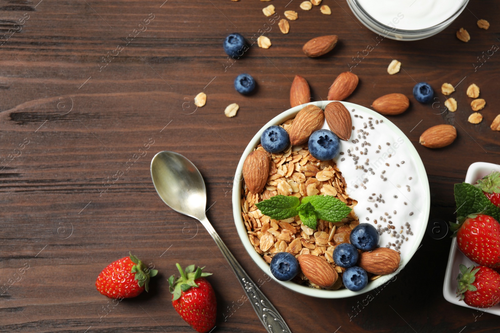 Photo of Tasty homemade granola with yogurt on wooden table, flat lay. Healthy breakfast