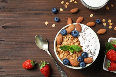 Photo of Tasty homemade granola with yogurt on wooden table, flat lay. Healthy breakfast