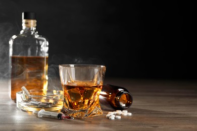 Photo of Alcohol and drug addiction. Whiskey in glass, syringe, pills and cigarettes on wooden table, space for text