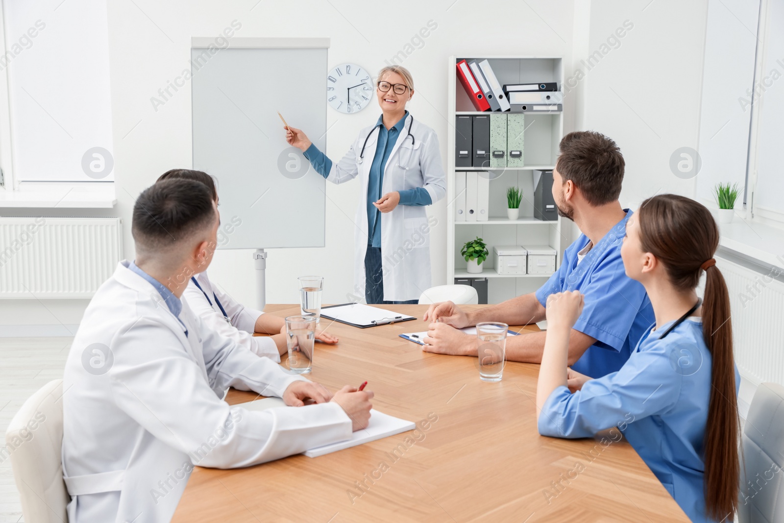 Photo of Doctor giving lecture near flipchart in conference room