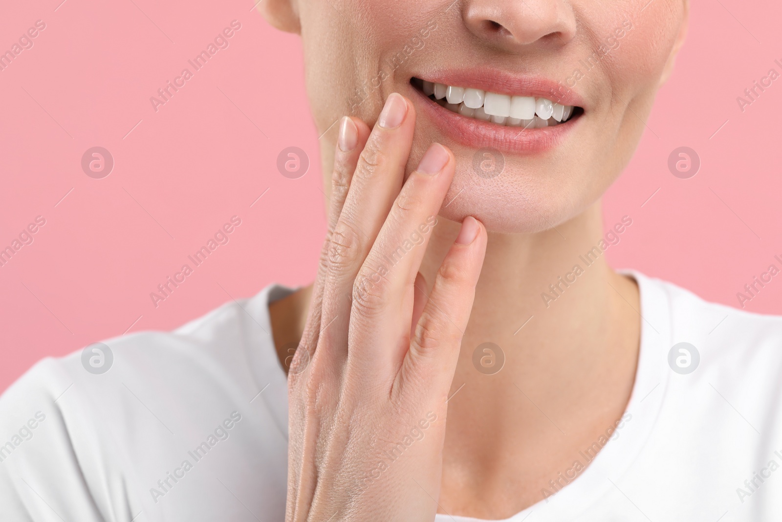 Photo of Woman with clean teeth smiling on pink background, closeup