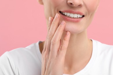 Woman with clean teeth smiling on pink background, closeup