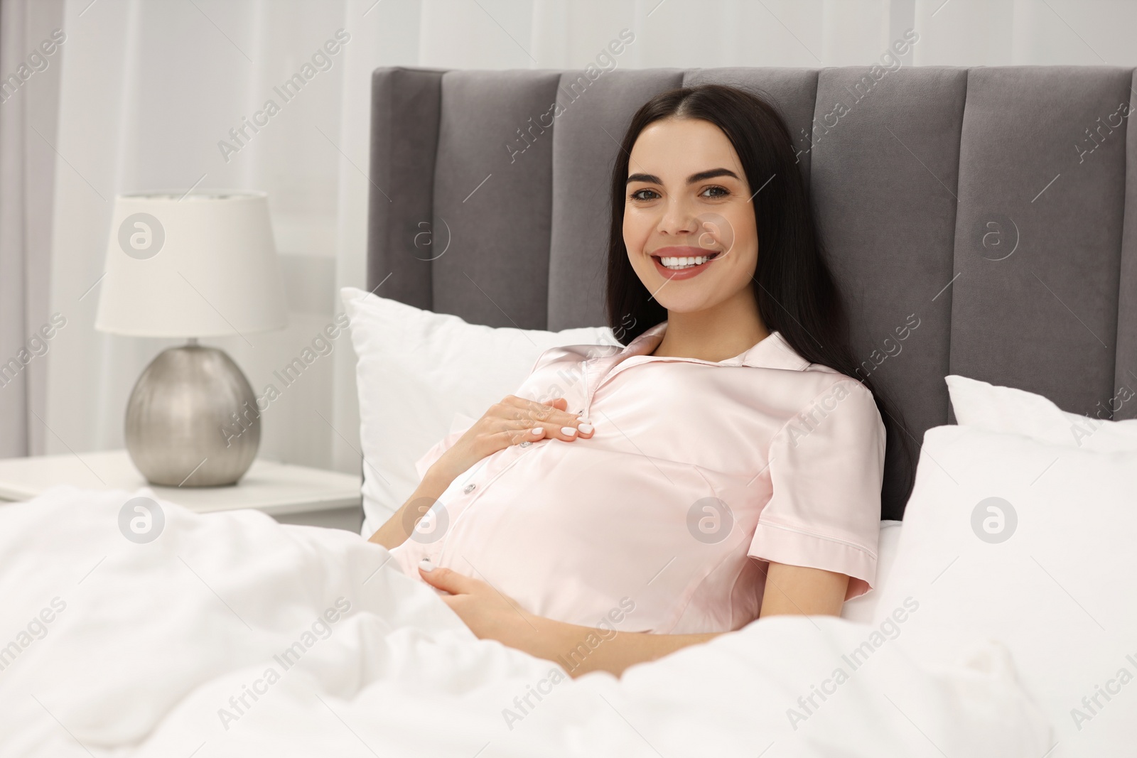 Photo of Happy pregnant woman in bed at home