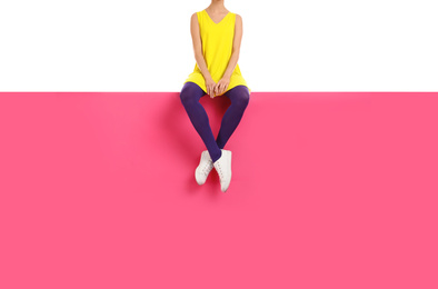 Photo of Woman wearing purple tights and stylish shoes sitting on color background, closeup