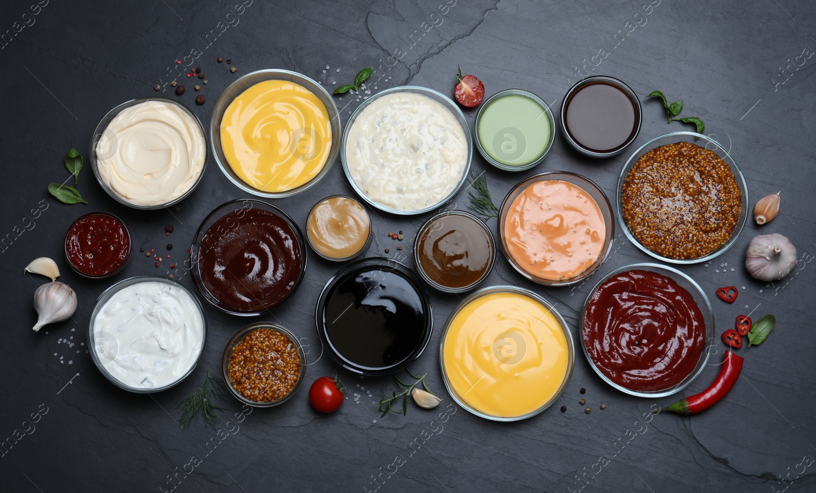 Photo of Many different sauces on black table, flat lay