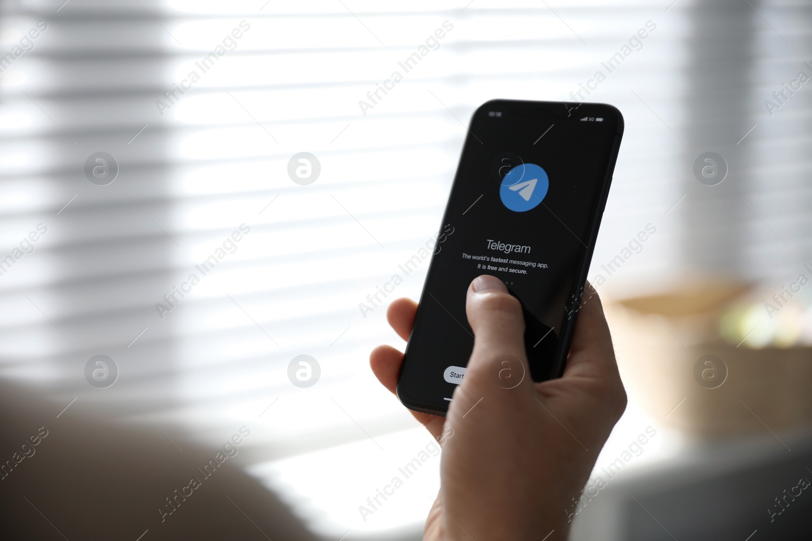 Photo of MYKOLAIV, UKRAINE - MARCH 16, 2020: Man holding iPhone 11 with Telegram app on screen indoors, closeup