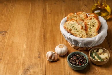 Photo of Tasty baguette with garlic, oil and other spices on wooden table, space for text