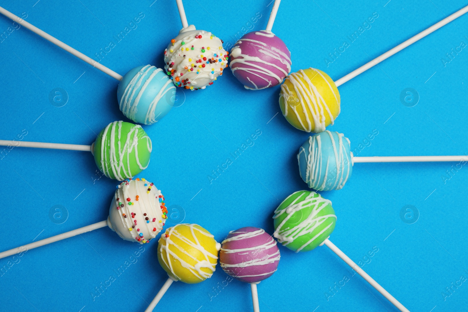 Photo of Frame made of bright delicious cake pops on color background, flat lay. Space for text