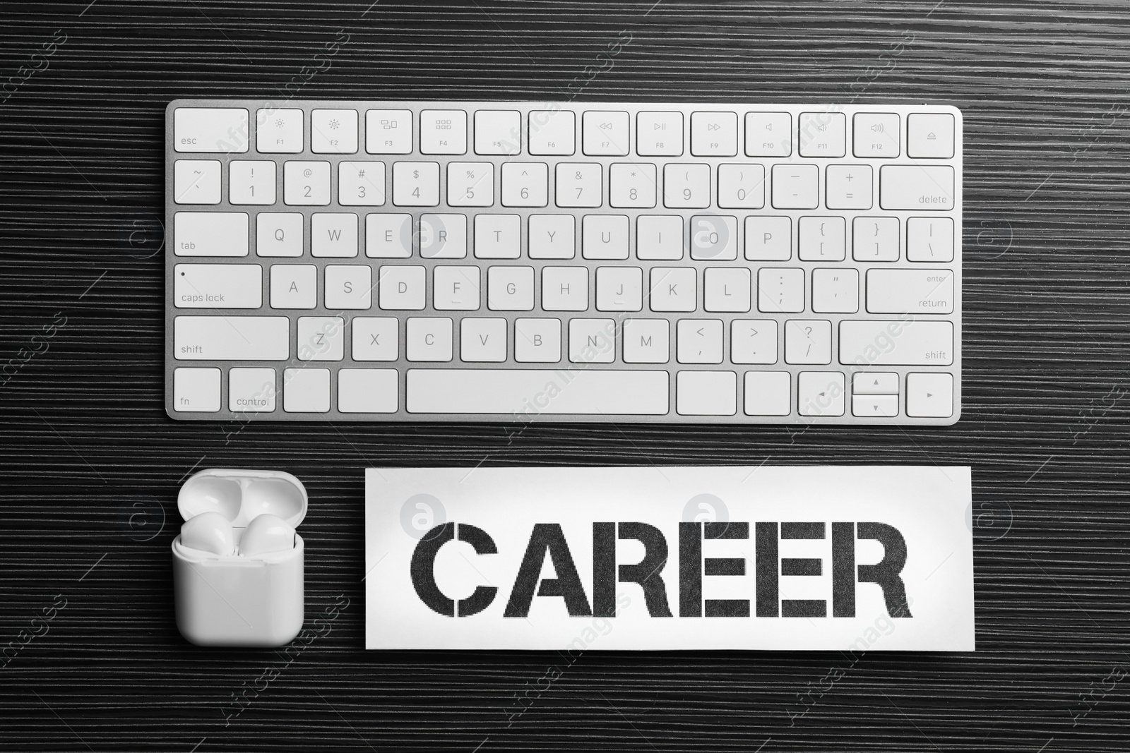 Photo of Flat lay composition with word CAREER, computer keyboard and earphones on black wooden table