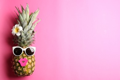Top view of funny pineapple with sunglasses, lips and plumeria flower on pink background, space for text. Creative concept