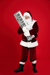 Santa Claus with synthesizer on red background. Christmas music