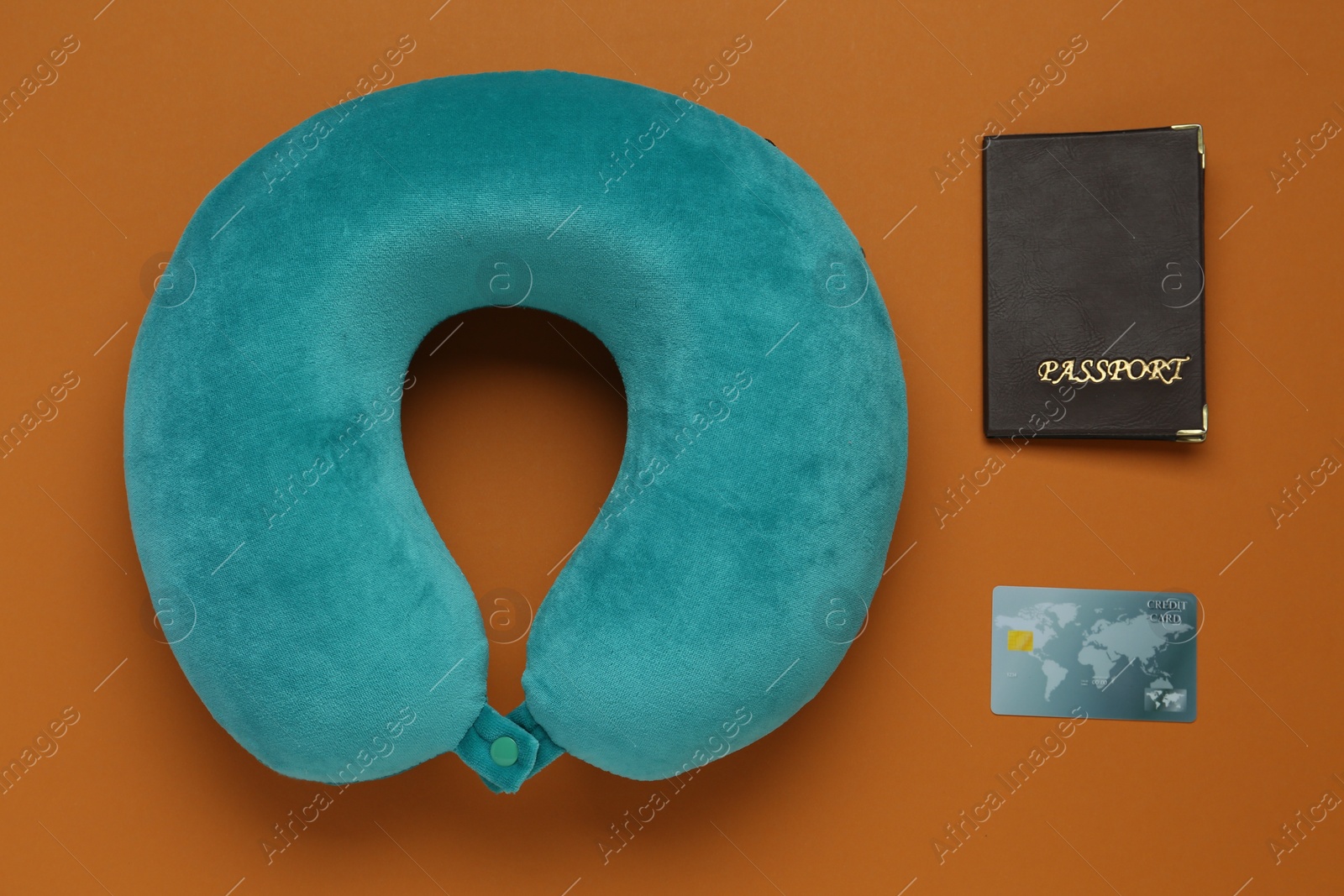 Photo of Turquoise pillow, passport and credit card on orange background, flat lay