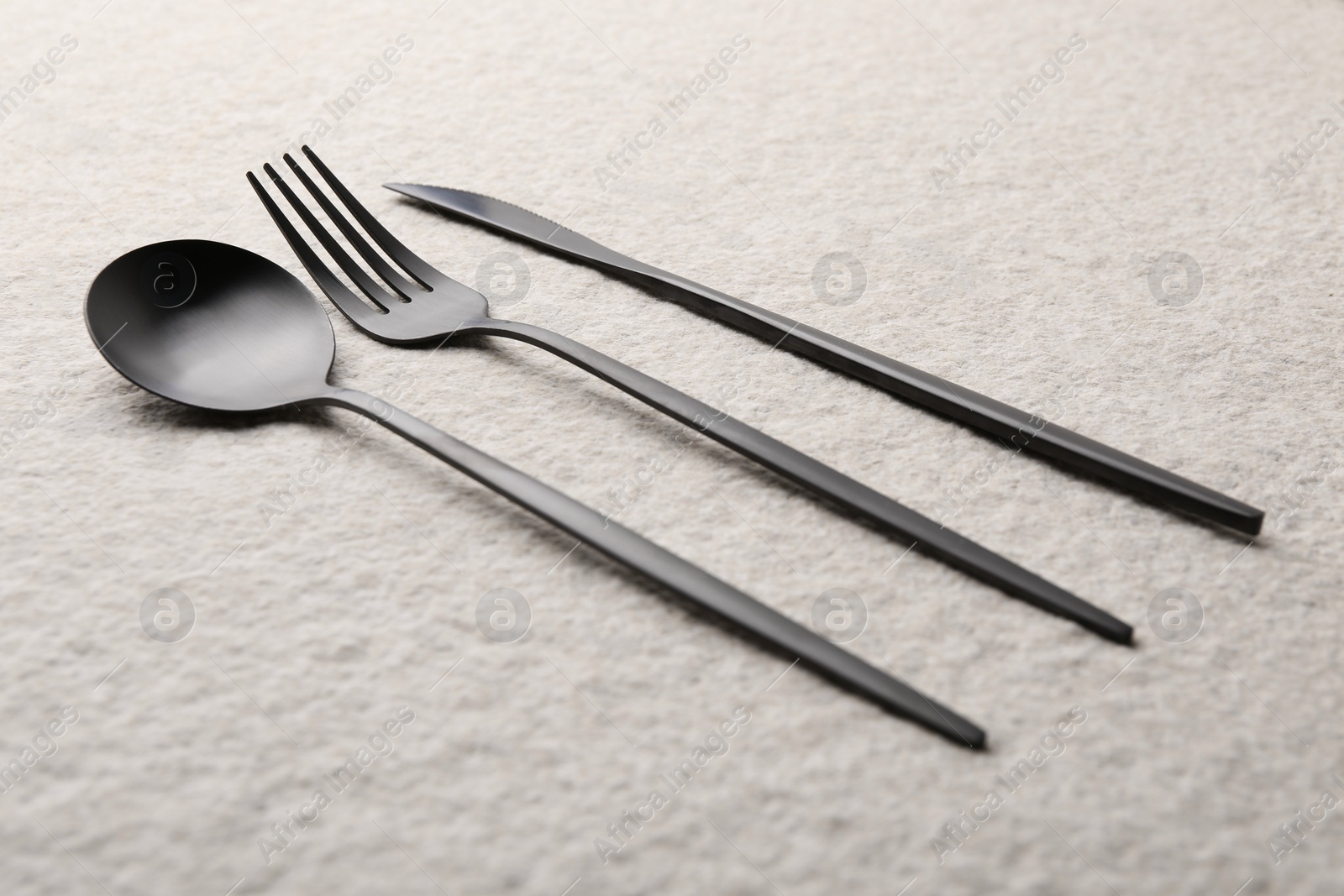 Photo of Stylish cutlery set on beige textured table, closeup