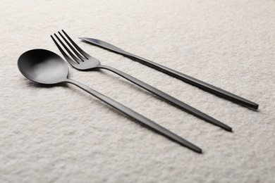 Stylish cutlery set on beige textured table, closeup