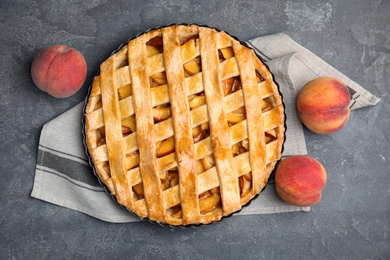 Photo of Delicious peach pie and fresh fruits on grey table, flat lay