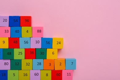 Photo of Wooden cubes with different numbers on light pink background, flat lay. Space for text