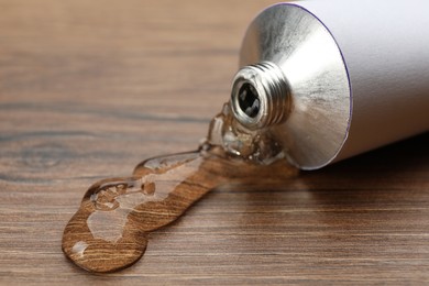 Photo of Open white tube with ointment on wooden table, closeup