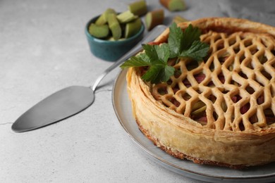 Photo of Freshly baked rhubarb pie and cake server on light grey table, closeup