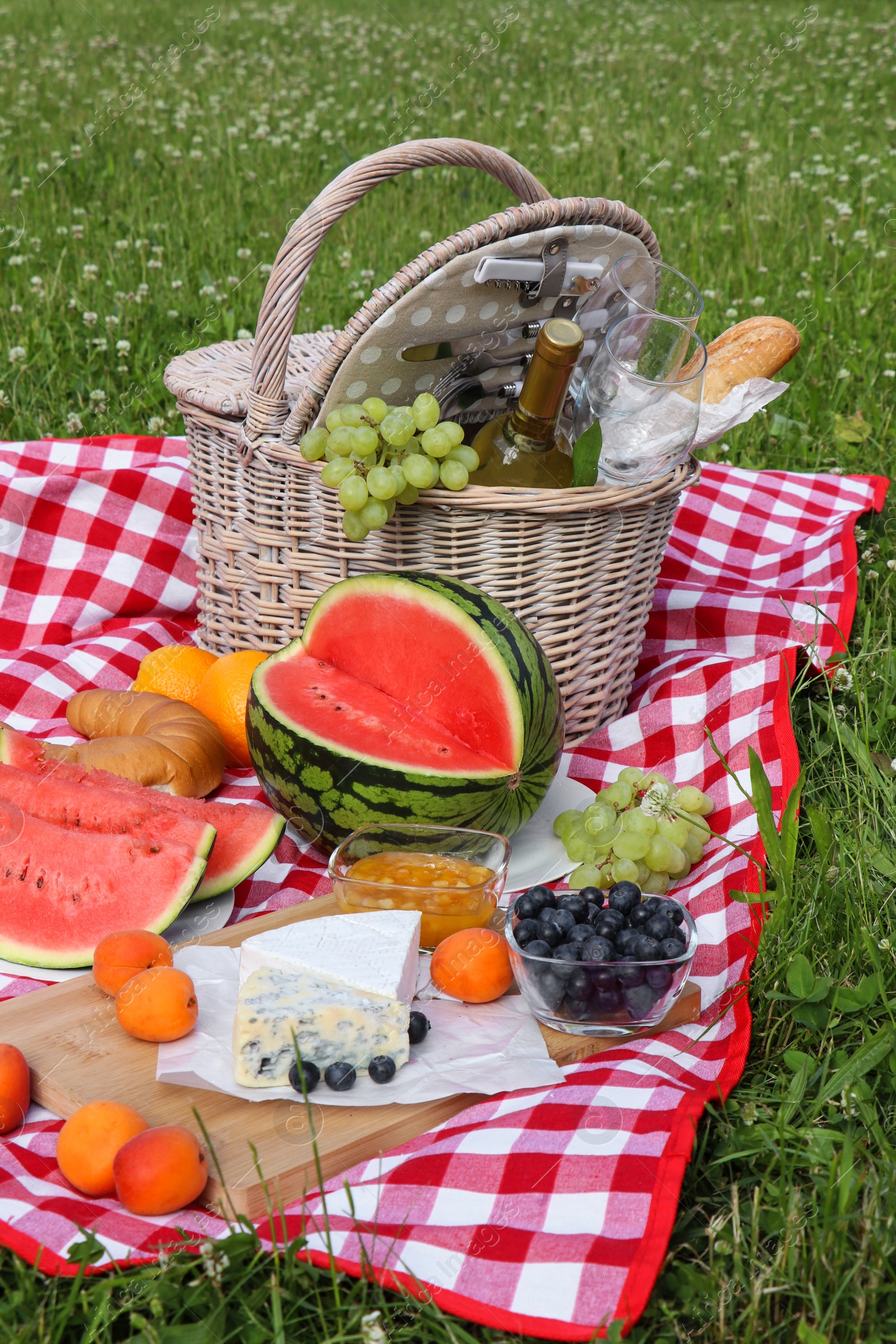 Photo of Picnic blanket with delicious food and wine outdoors on summer day