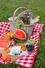 Photo of Picnic blanket with delicious food and wine outdoors on summer day