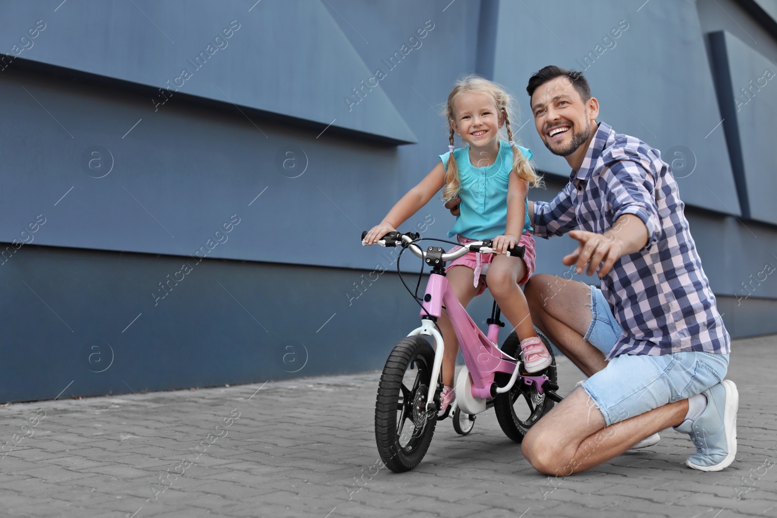 Photo of Father teaching daughter to ride bicycle on street