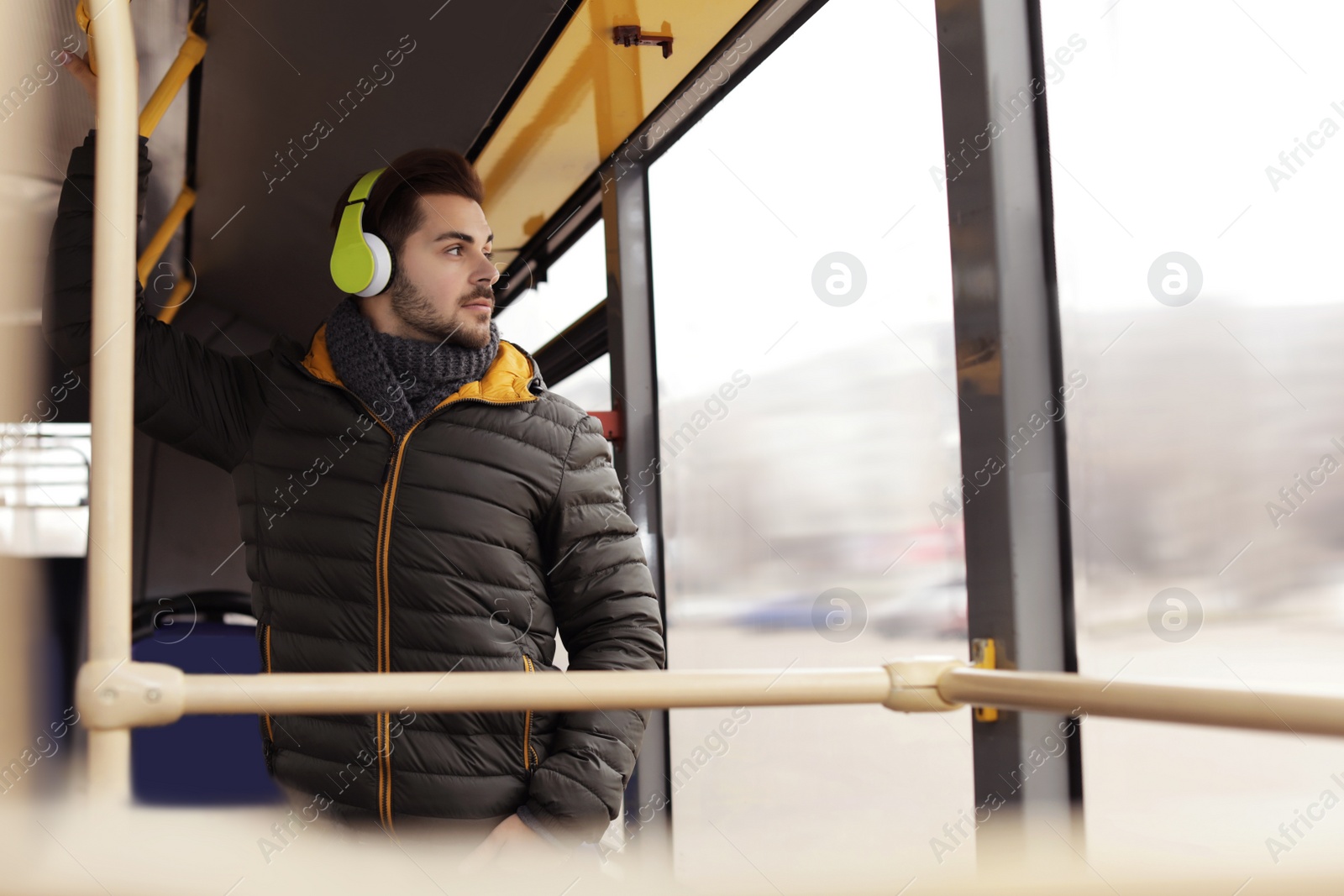 Photo of Young man listening to music with headphones in public transport