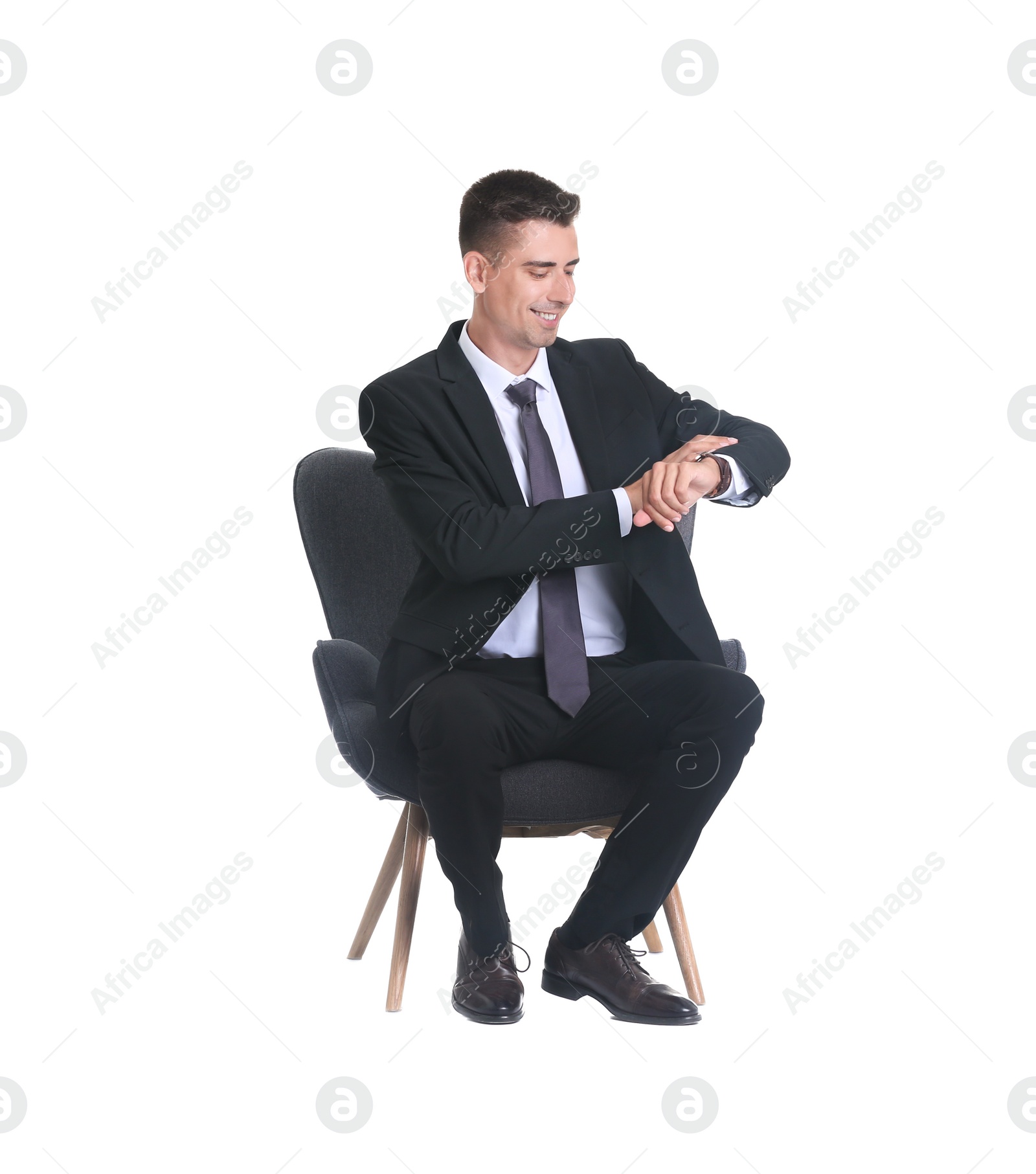 Photo of Handsome young man in suit sitting in armchair on white background