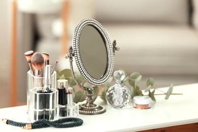Mirror and makeup products on white table indoors