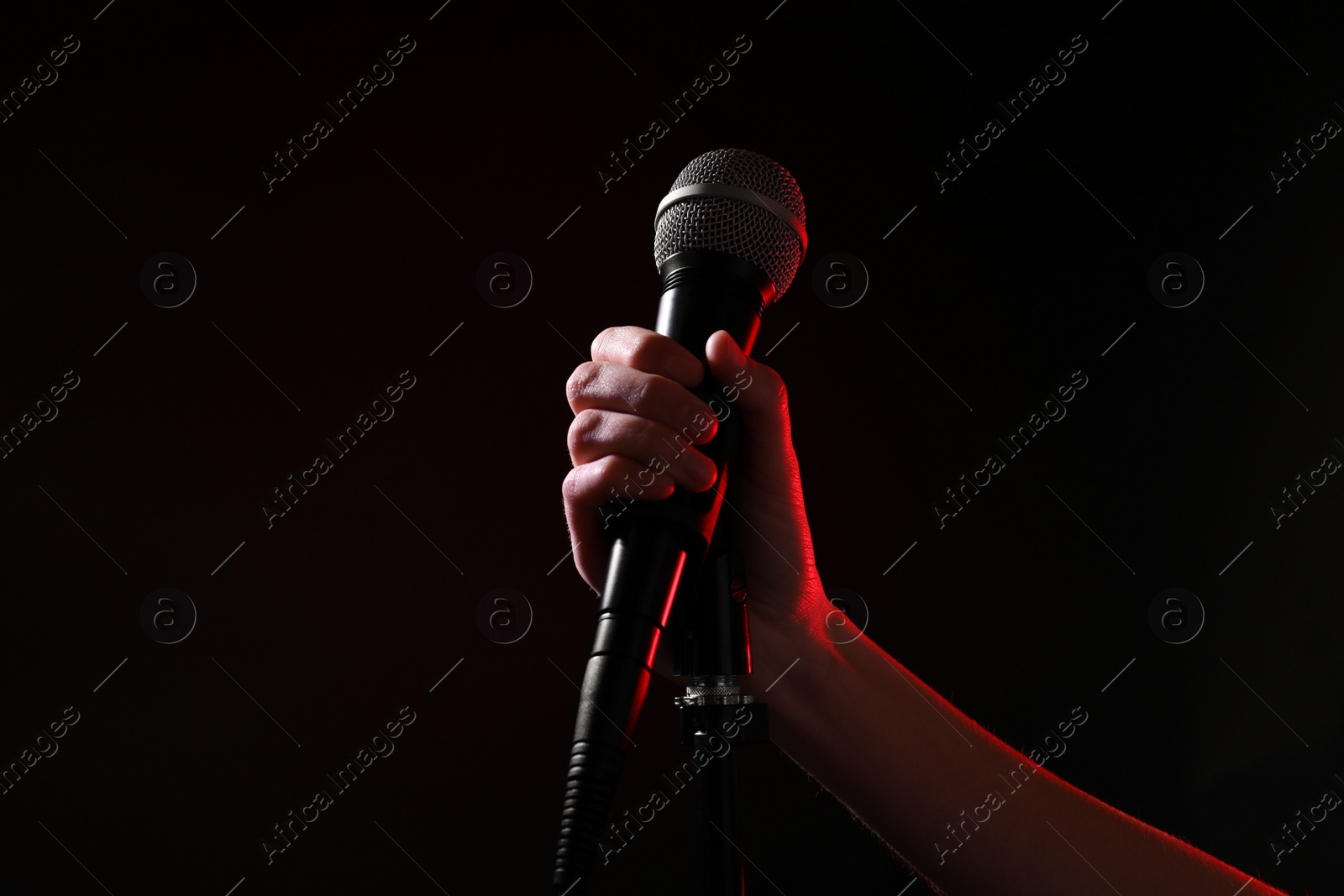 Photo of Woman holding microphone on black background, closeup