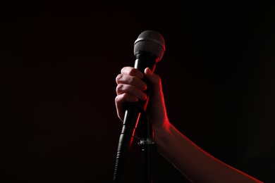 Photo of Woman holding microphone on black background, closeup