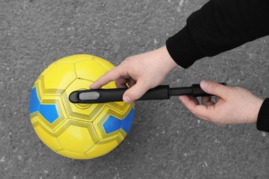 Photo of Man inflating ball with manual pump on asphalt, top view