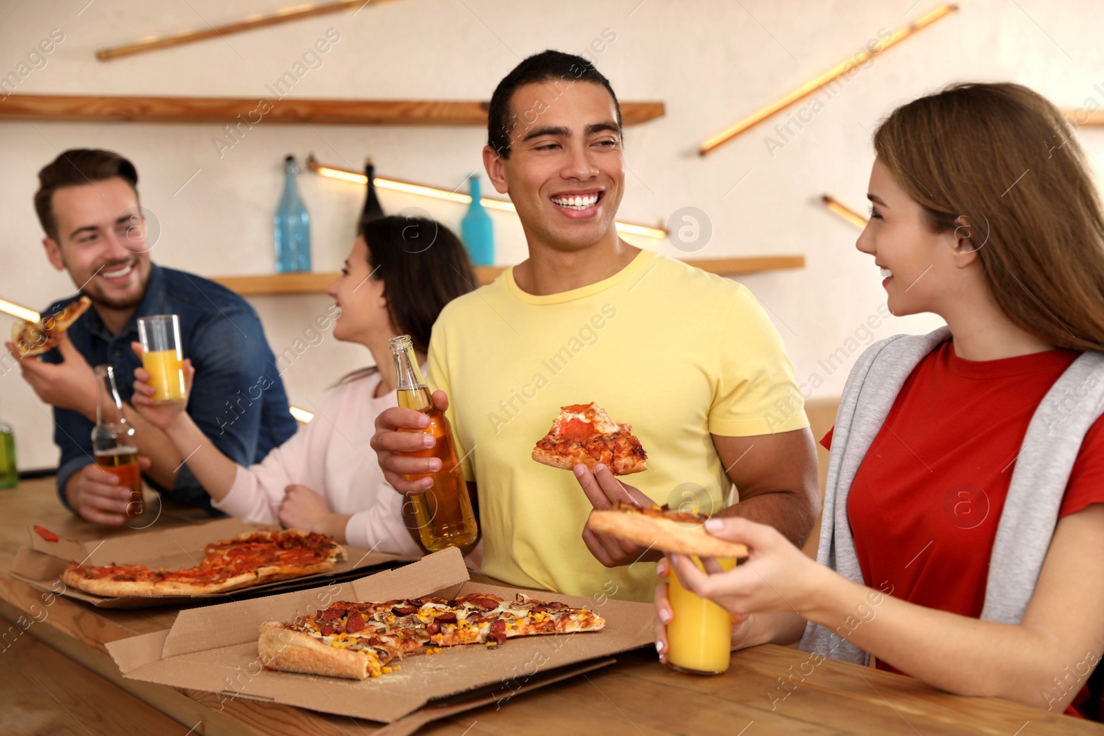 Photo of Group of friends having fun party with delicious pizza in cafe