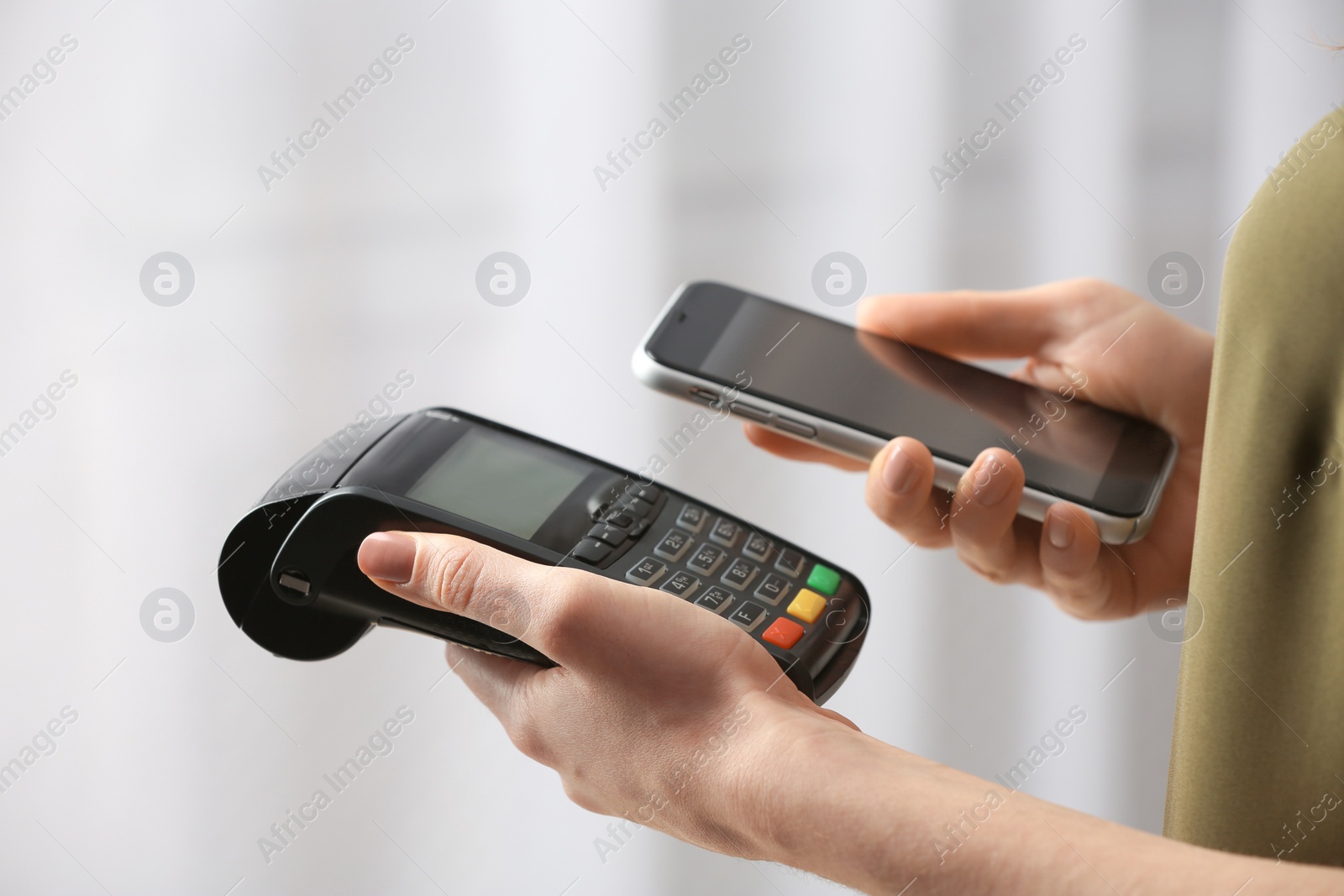 Photo of Woman using modern payment terminal with mobile phone indoors, closeup