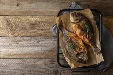 Photo of Delicious dorado fish with rosemary on wooden table, top view. Space for text