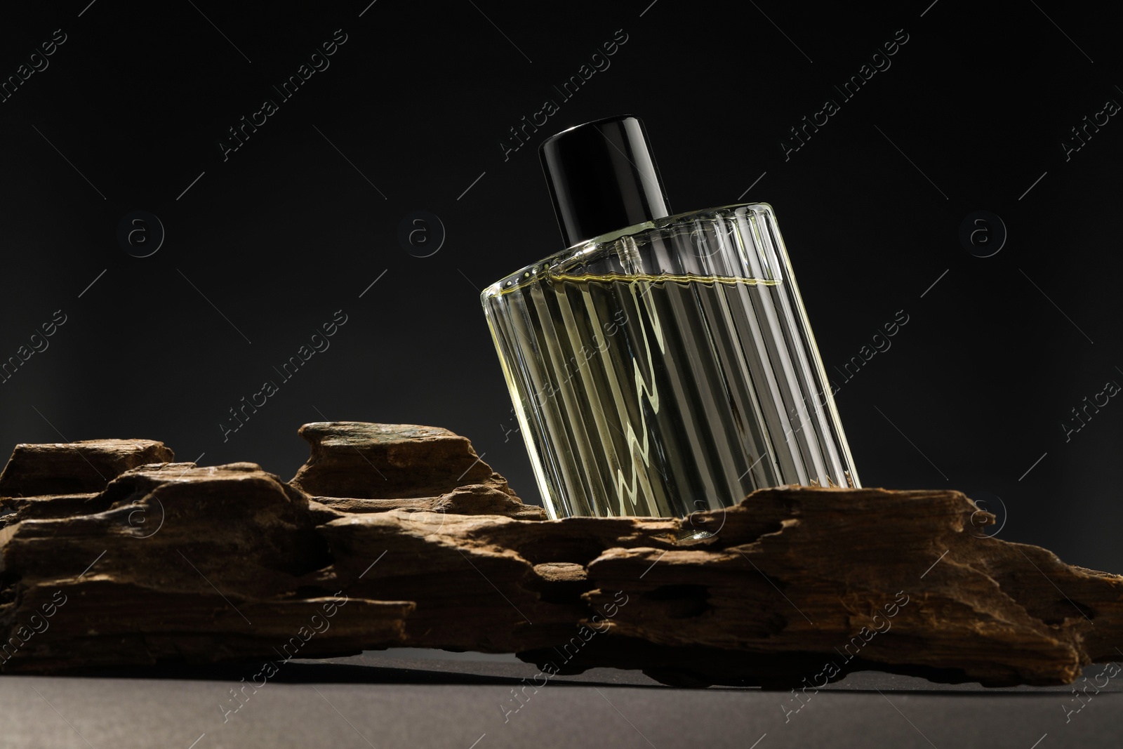 Photo of Luxury men`s perfume in bottle on grey table against dark background, space for text